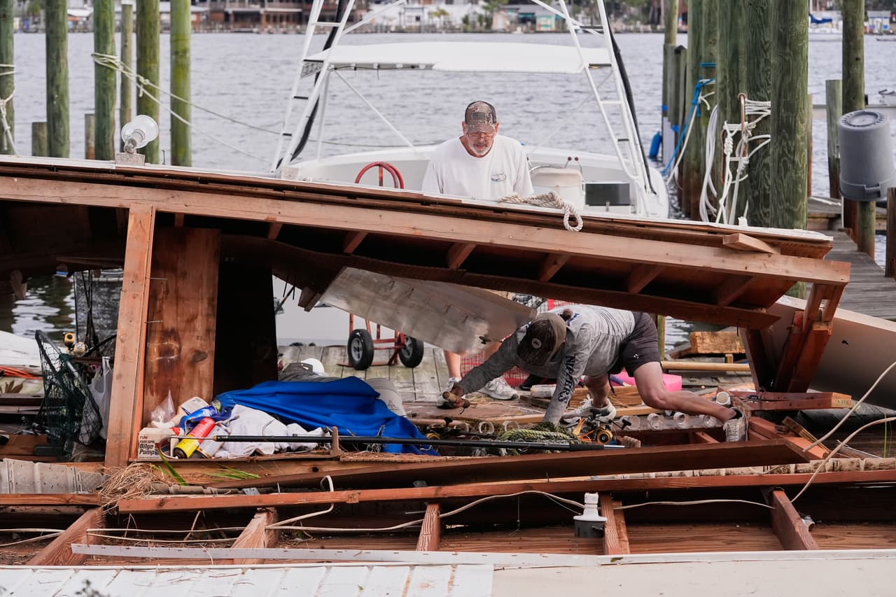 Varias personas recuperan sus pertenencias de un cobertizo para botes derrumbado tras el paso del huracán Isaias en Destin, Florida, el sábado 10 de octubre de 2026.