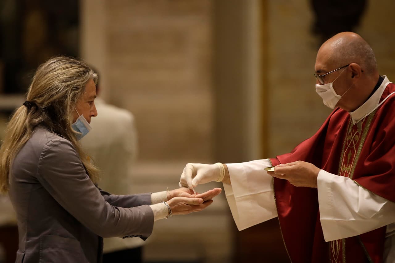 Una mujer junto a un sacerdote en la Iglesia San Eugenio en Roma el 18 de mayo del 2020. (AP Photo/Alessandra Tarantino)