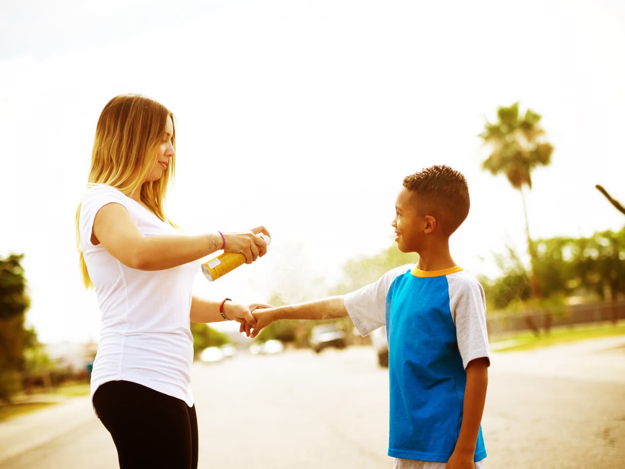 Tal como si fuera un día de playa, una madre protege a su hijo de los rayos solares con bloqueador sobre la piel, en una calle al oeste de Phoenix.