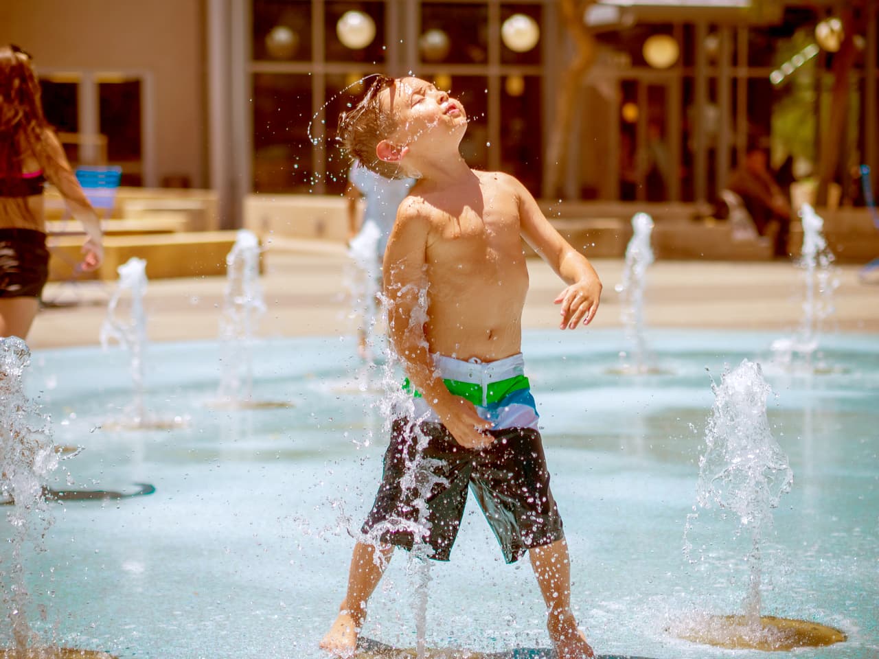 Un niño se refresca por la tarde en la fuente del Cityscape de Phoenix. Este centro de comercios y restaurantes ofrece cada verano una fuente para refrescar a los habitantes de la ciudad, y en invierno el mismo espacio es convertido en una pista de patinaje sobre hielo.