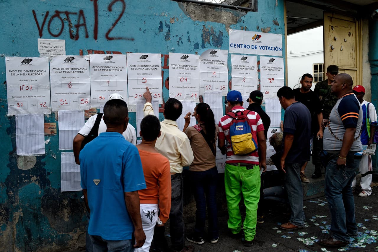 Un grupo de votantes busca sus nombres en un centro electoral de Caracas.