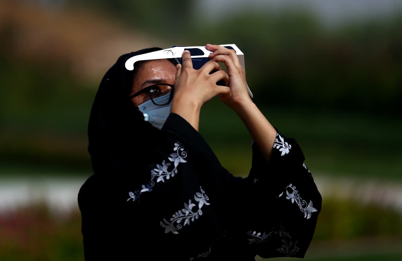 Una mujer en Dubai contempla el eclipse usando unos lentes especiales que vendió el centro astronómico del país. Hasan al-Hariri, director del instituto, dijo: "Un eclipse es un evento raro. Usualmente suceden un par de veces al año, pero difiere de ubicación a ubicación, así que no es algo fijo en un lugar.