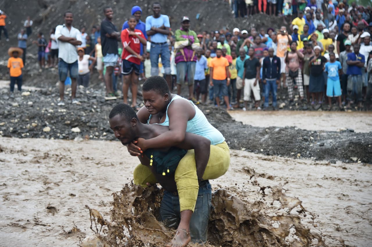 Un puente sobre el río Petit Goave en Port-au-Prince, Haití, colapsó por las fuertes lluvias, lo que obliga a los habitantes a cruzar el río a pie.