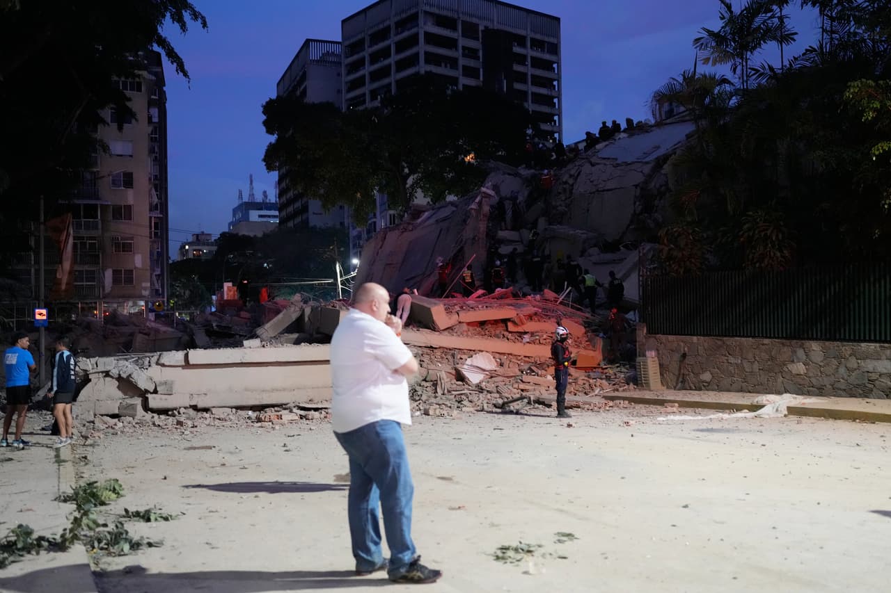 Un hombre permanece de pie junto a un edificio derrumbado tras los movimientos telúricos.