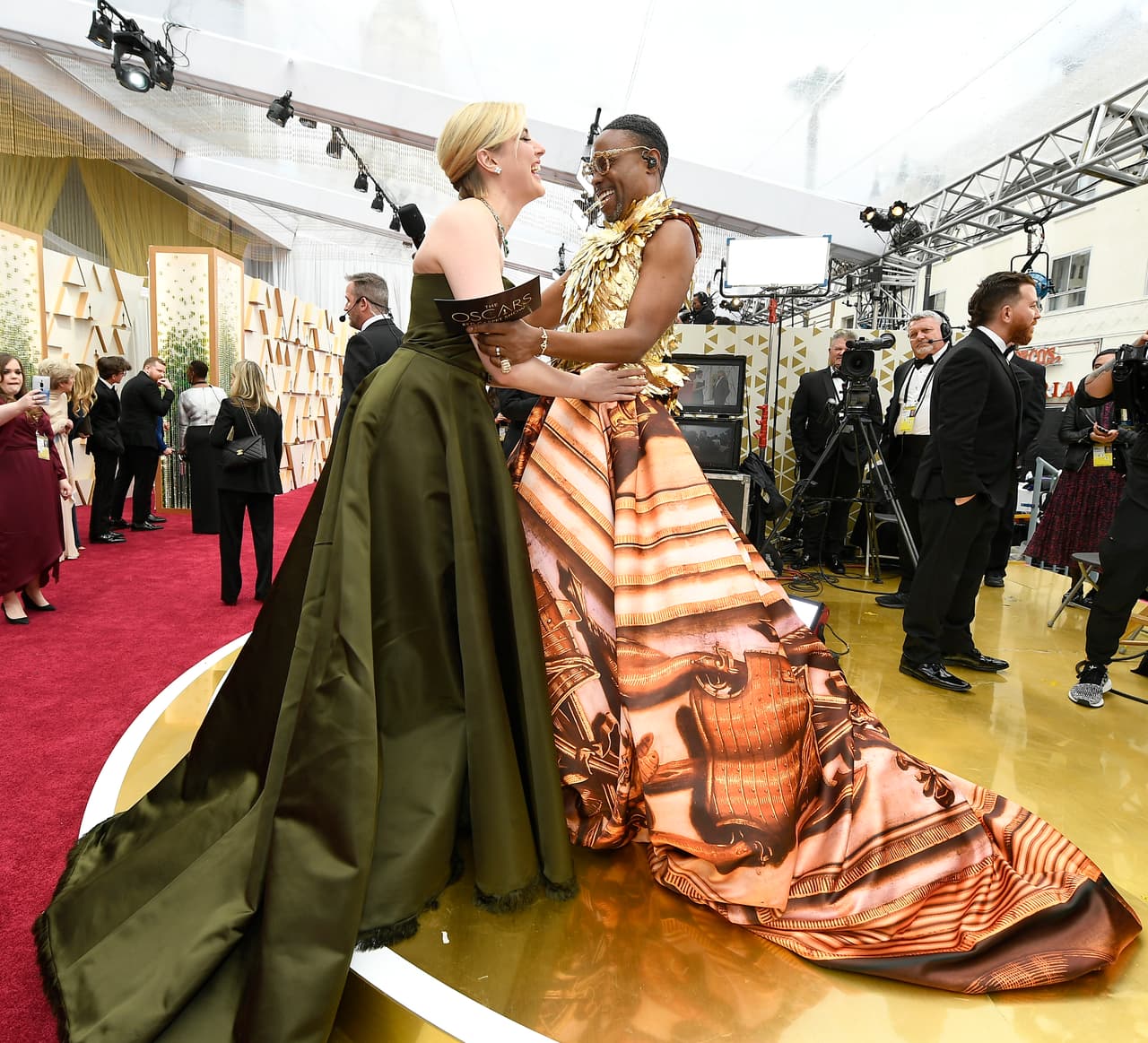 El vestido tenía en la parte superior un top de plumas doradas, sin mangas y de cuello alto. Abajo, destacó una falda globo estampada en tonos anaranjados y con motivos clásicos y heráldicos.
<br>