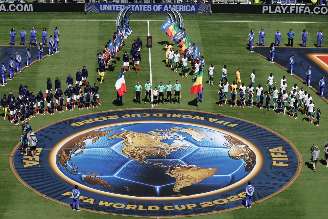 Jugadores franceses (a la izquierda) y senegaleses permanecen de pie antes del partido de fútbol del Grupo I de la Copa del Mundo entre Francia y Senegal en East Rutherford.