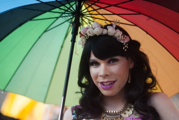 Una persona marcha por las calles de Chile con un vestido de princesa y un paraguas.