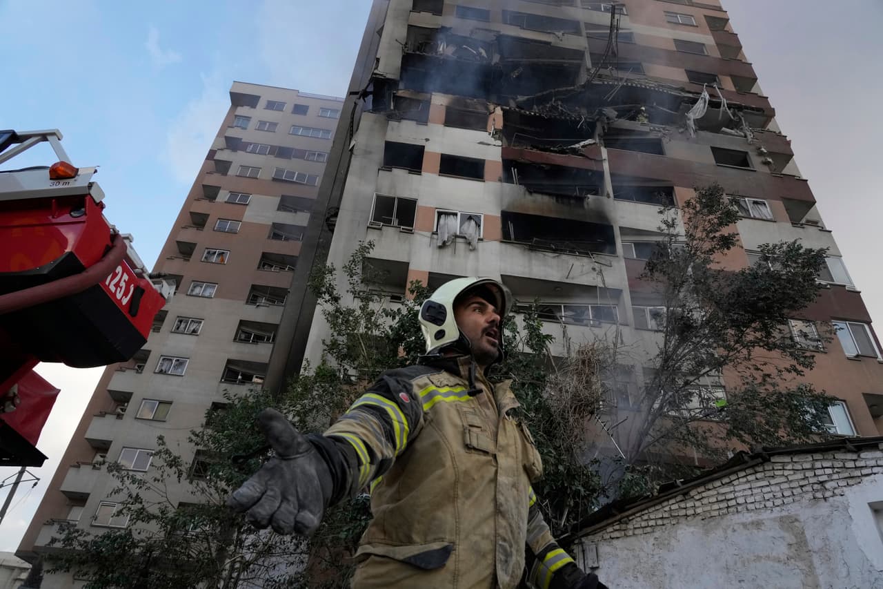 Un bombero frente a un edificio residencial de Teherán, Irán, el viernes 13 de junio de 2025 donde se registró una explosión. Israel atacó diversos puntos de la capital iraní la madrugada del viernes.
<br>