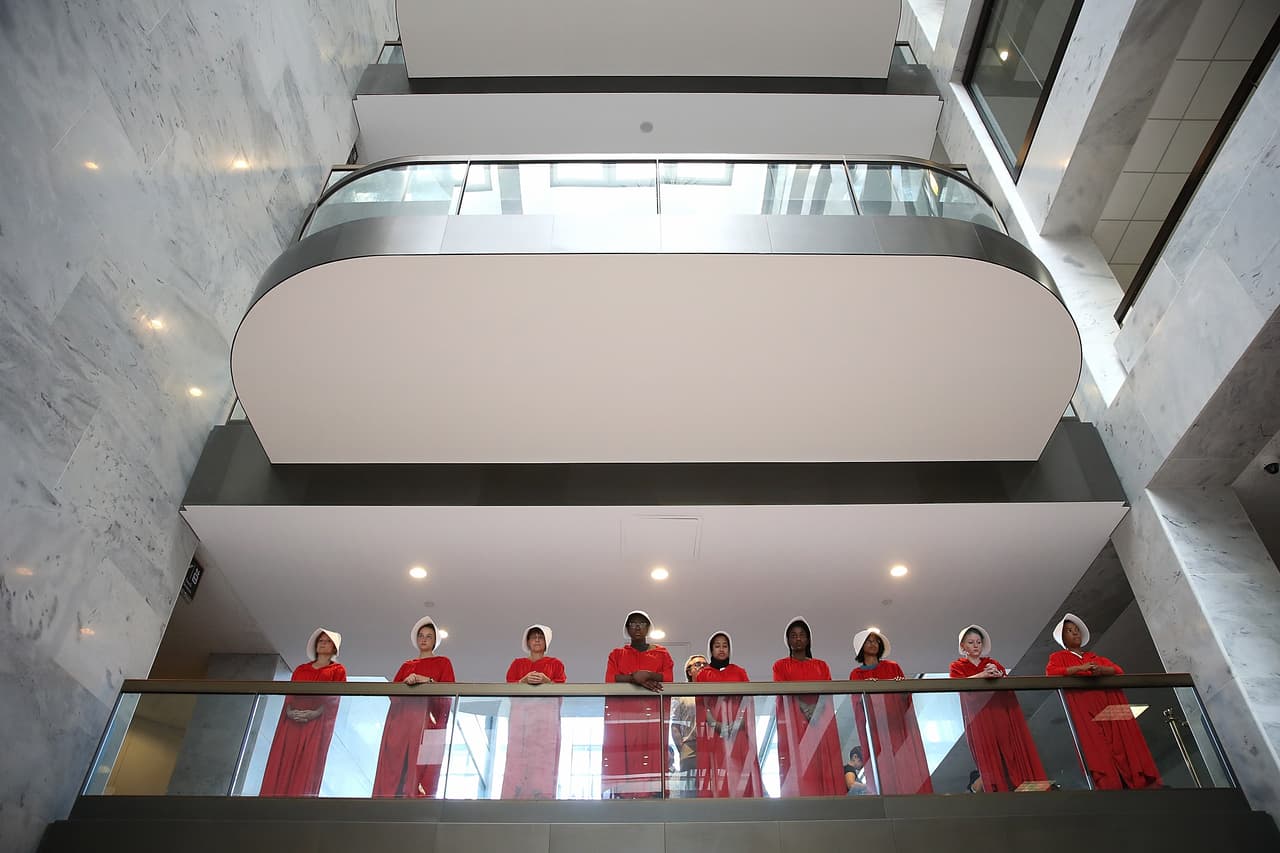 WASHINGTON, DC - SEPTEMBER 04: Protesters dressed in The Handmaid's Tale costume, protest outside the hearing room where Supreme Court nominee Judge Brett Kavanaugh will testify before the Senate Judiciary Committee during his Supreme Court confirmation hearing in the Hart Senate Office Building on Capitol Hill September 4, 2018 in Washington, DC. Kavanaugh was nominated by President Donald Trump to fill the vacancy on the court left by retiring Associate Justice Anthony Kennedy. (Photo by Win McNamee/Getty Images)