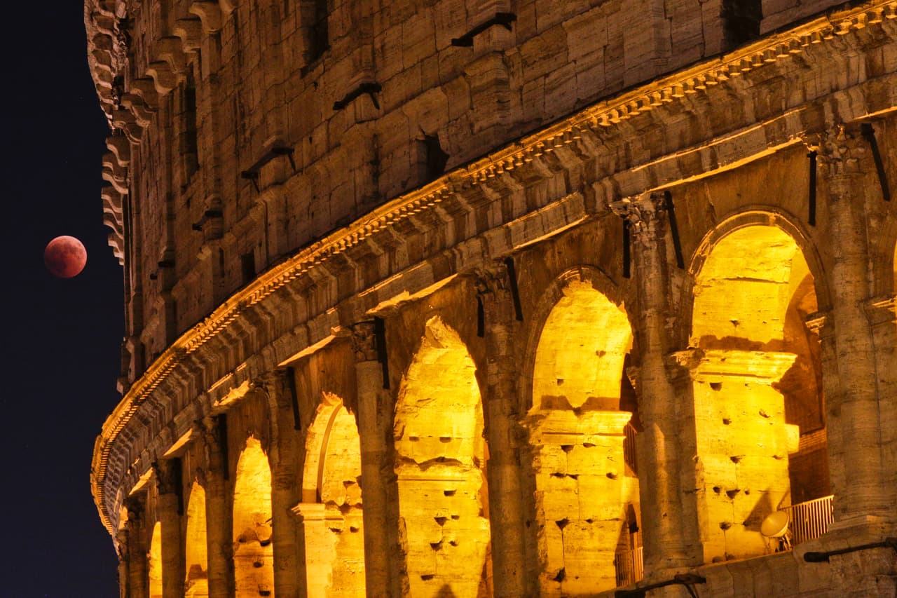 La Luna se eleva al lado del Coliseo de Roma.