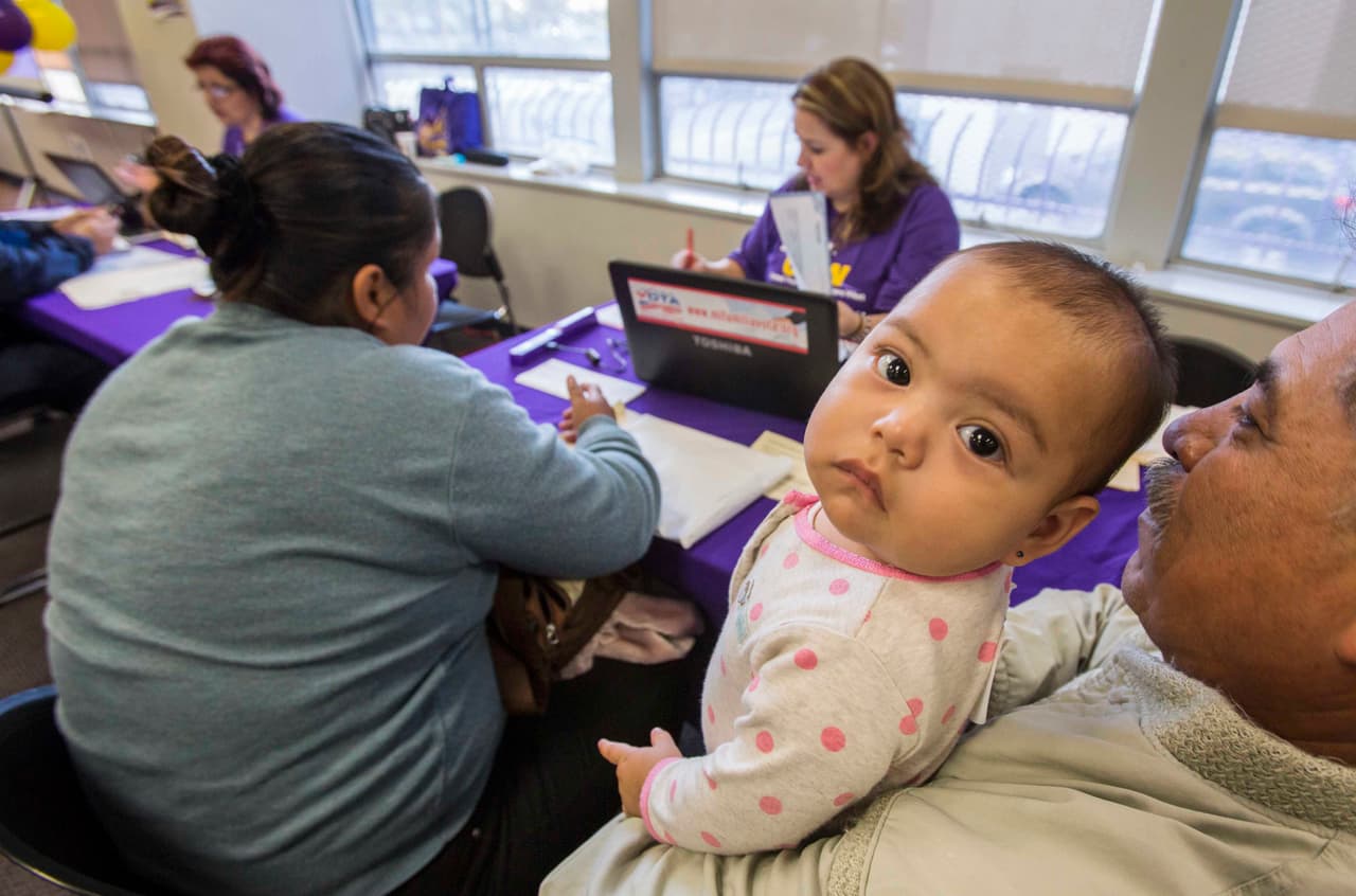 Maria Robles, left, 37, with her daughter Daniela Oliuares, 1, and her husband Martin Oliuares, 51, are assisted by SEIU-UHW worker during a health care enrollment event at SEIU-UHW office, Monday, March 31, 2014, in Commerce, Calif. Monday marks this year's open enrollment deadline, but consumers will get extra time to finish their applications. (AP Photo/Ringo H.W. Chiu)