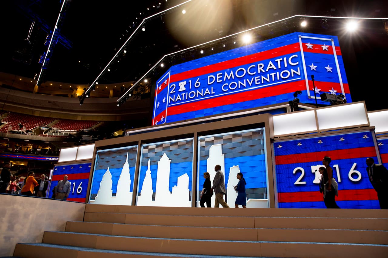 DOMINGO 24 DE JULIO. 7:09 PM. Algunas personas caminan por la tarima desde donde hablarán a los delegados los participantes en la convención demócrata. Desde este espacio darán sus discursos Barack y Michelle Obama, Bernie Sanders y Hillary Clinton, entre muchos otros.