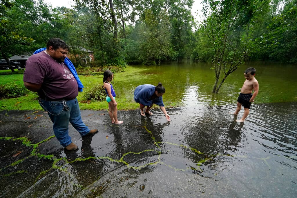 Una familia, frente a su casa rodeada de agua en Slidell.