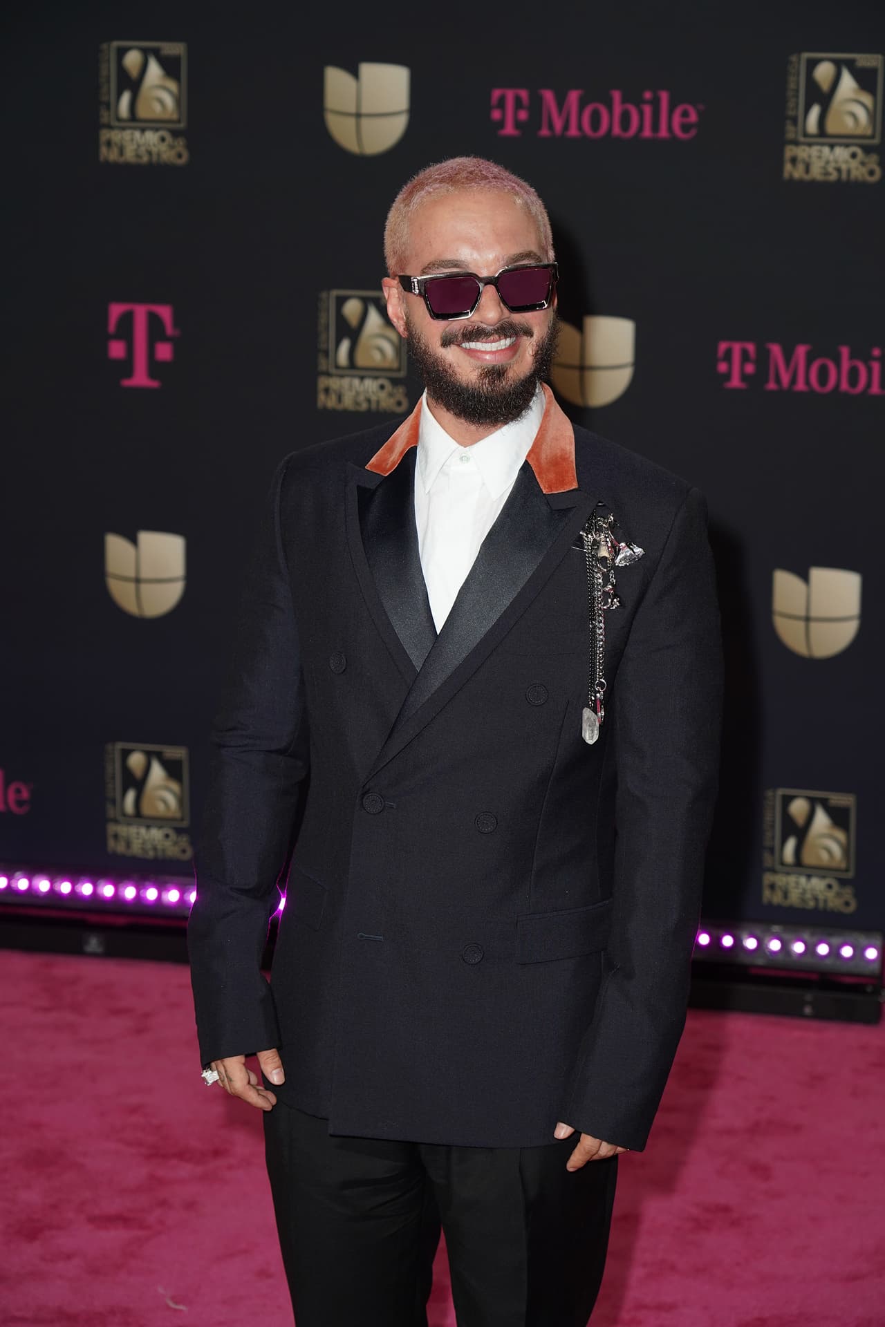 El reggaetonero llevó un traje cruzado negro con solapas satinadas y detalles de color en el cuello. Accesorizó con gafas oscuras y pins en el bolsillo.