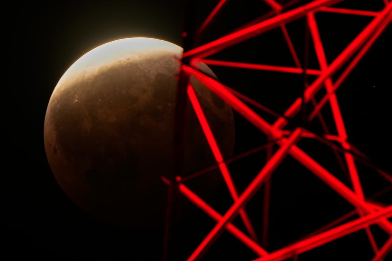 La madrugada del 28 de agosto de 2026, en Kansas City, Misuri, se observa un eclipse lunar parcial más allá de una torre de televisión.