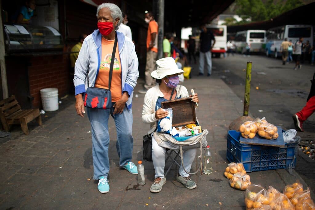 Vendedores callejeros usan mascarillas para protegerse del nuevo coronavirus mientras esperan clientes en Caracas.