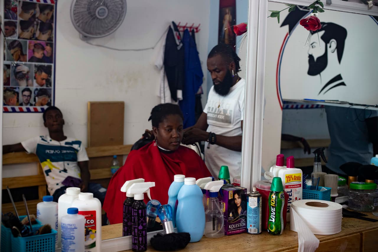 Una mujer haitiana recibe un corte de cabello en una barbería instalada por un ciudadano haitiano en Tapachula.
<br>