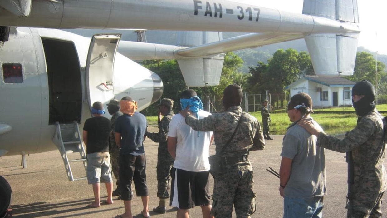 Persons arrested in a counter-drug operation board a Honduran military plane.