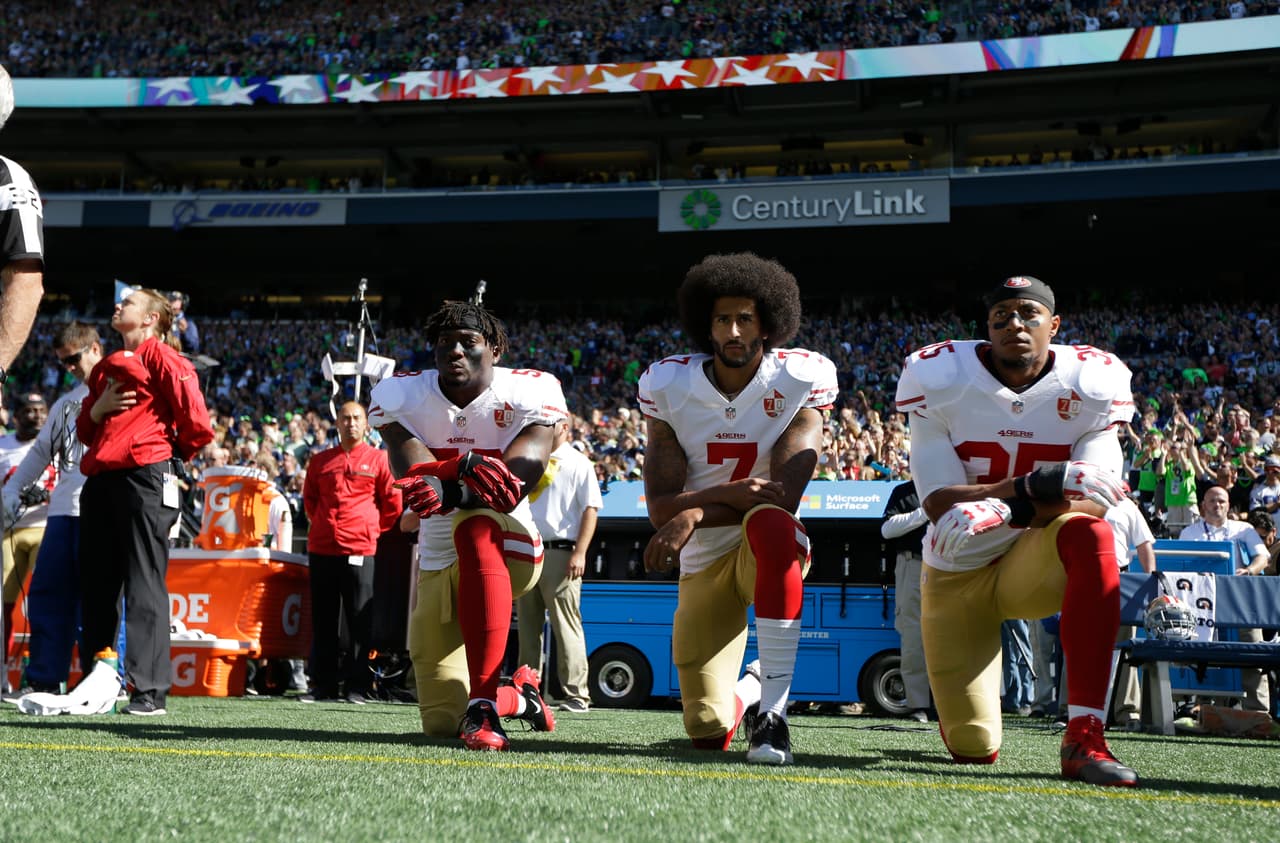 Colin Kaepernick (centro) inició con las protestas en la NFL.