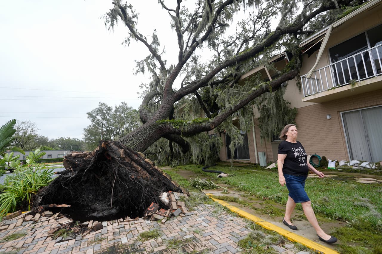 Joella Krzyzanski camina junto a un gran roble que cayó en su complejo de apartamentos después del paso del huracán Milton en Sanford, Florida.