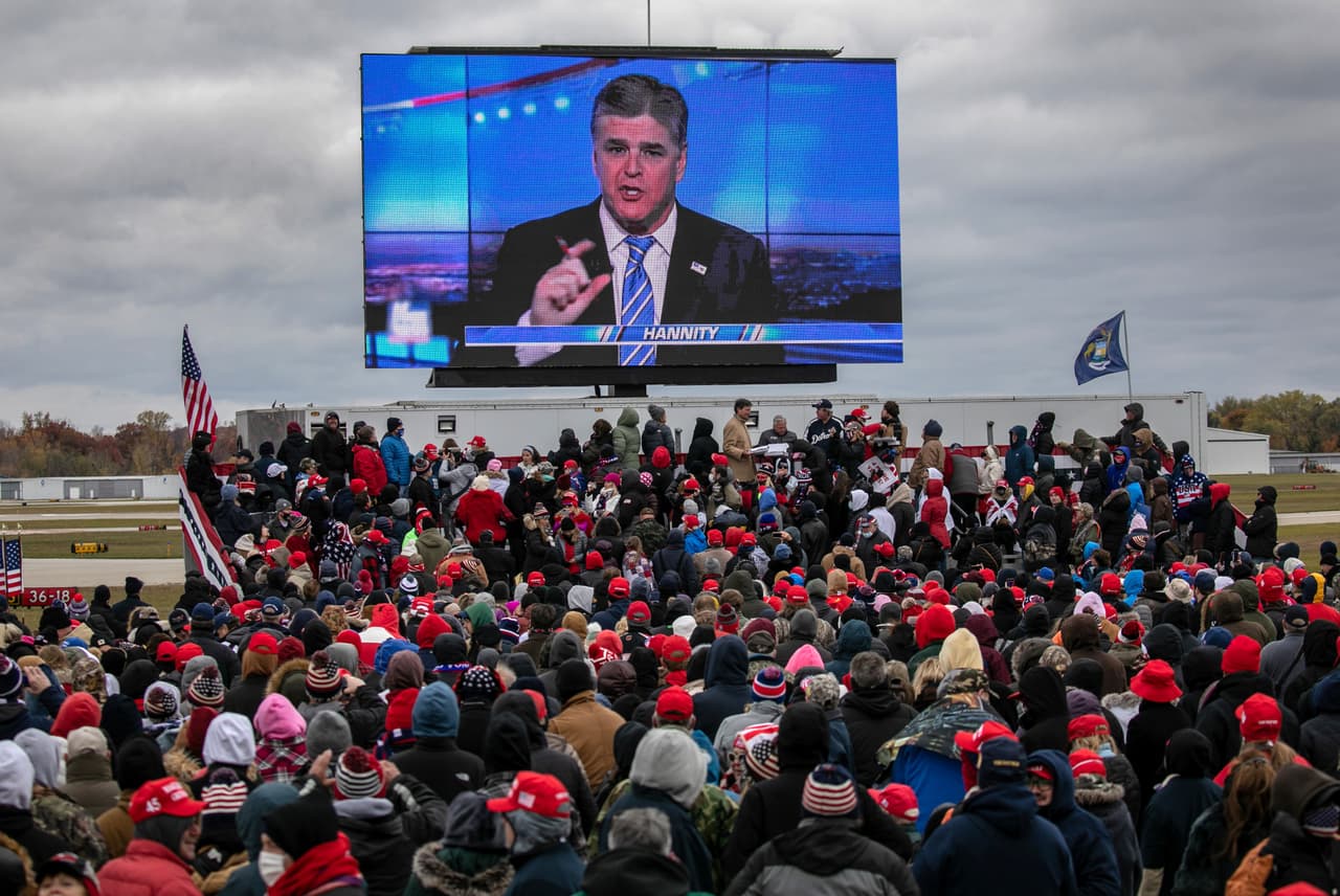 Simpatizantes del expresidente Donald Trump miran un video del presentador Sean Hannity, de Fox News, durante un mitin en Waterford, Michigan, el 30 de octubre de 2020.