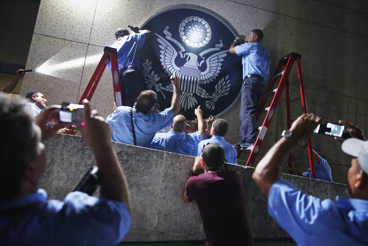 HAVANA, CUBA - AUGUST 14: U.S. Embassy employees hang the seal of the United States on the outside of the building a few hours before the ceremonial flag-raising August 14, 2015 in Havana, Cuba. U.S. Secretary of State John Kerry will visited Havana Friday and raised the American flag at the reopened U.S. embassy, a symbolic act after the the two former Cold War enemies reestablished diplomatic relations in July. (Photo by Chip Somodevilla/Getty Images)