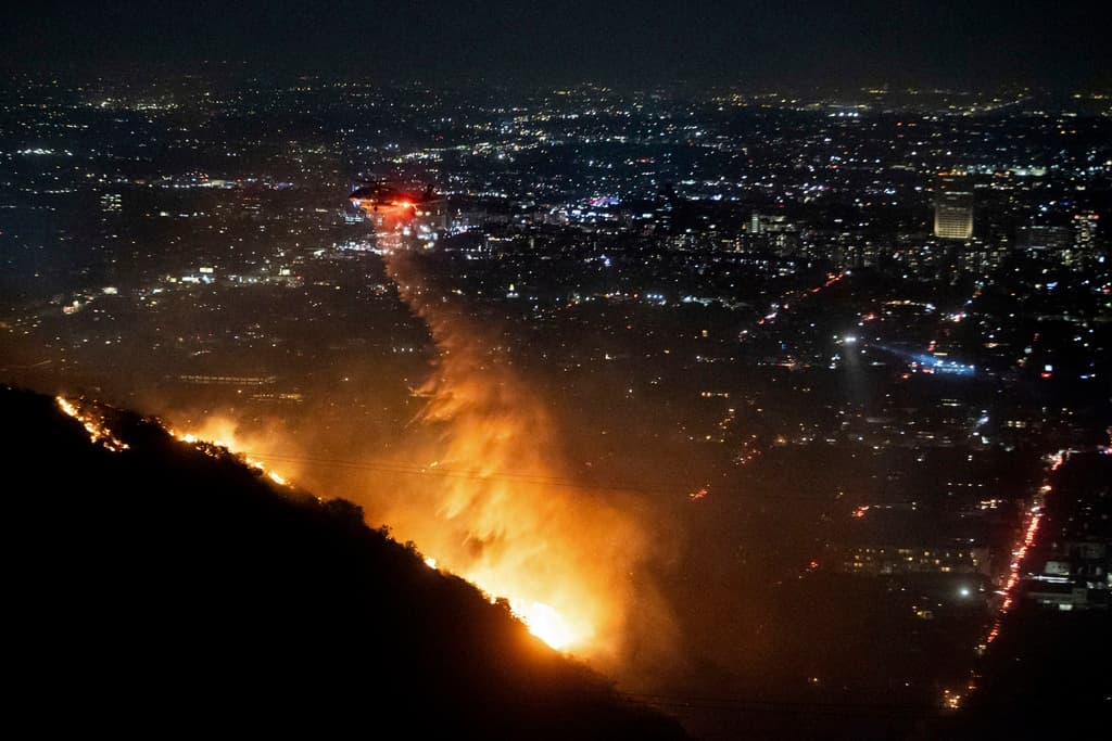 Un helicóptero suelta agua sobre las colinas de Hollywood,en donde arde el incendio Sunset.