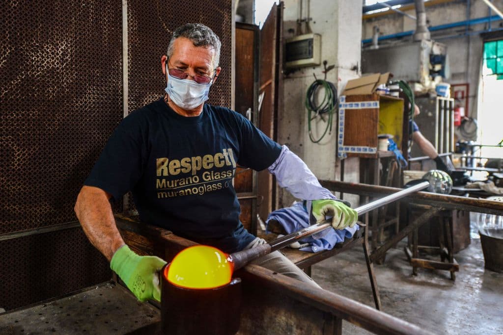 Un artesano hace vidrio soplado, este 18 de mayo en Murano, una de las isla que integra Venecia y que es mundialmente famosa por sus piezas de vidrio. Los museos, restaurantes, bares, cafeterías, peluquerías y otras tiendas han reabierto, sujetas a medidas de distanciamiento social.
