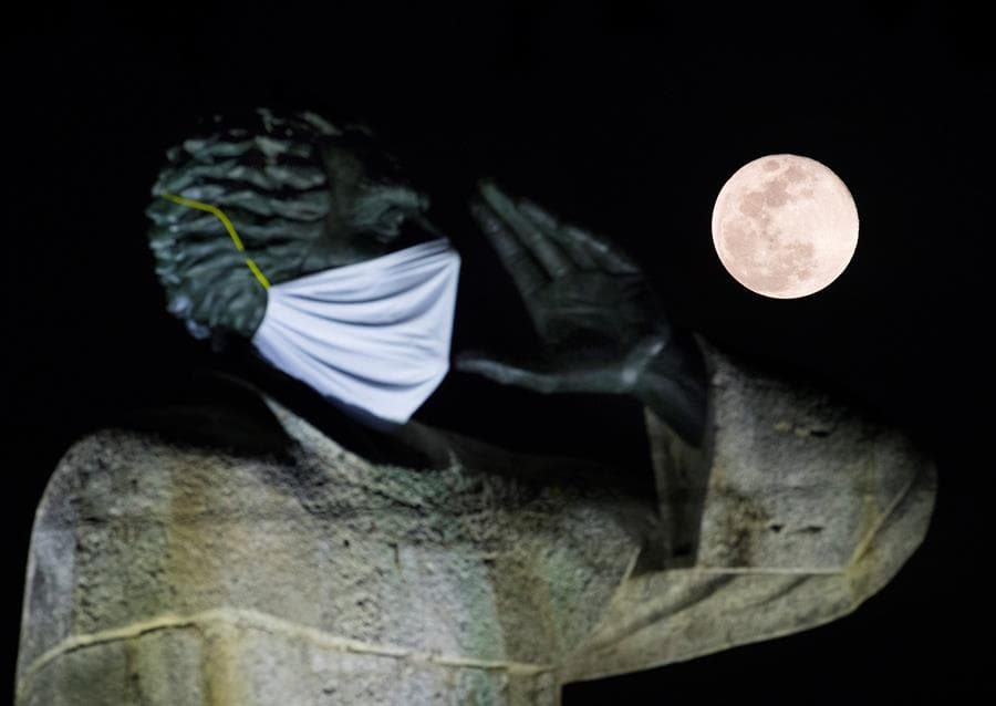 Fotografía de la luna llena junto a la estatua de fray Antonio de Montesino este jueves en Santo Domingo, República Dominicana. La estatua de 15 metros de altura tiene una mascarilla, una alusión a la pandemia de coronavirus.