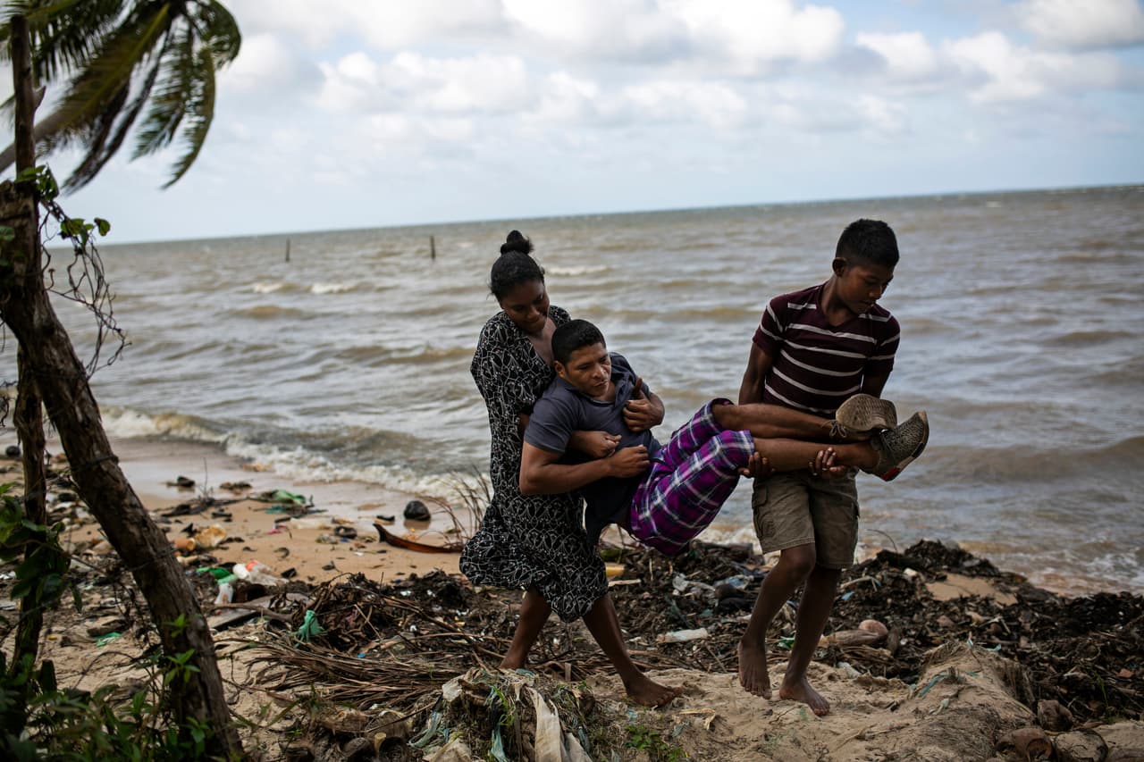 No es claro cuántos se han visto afectados por el síndrome, pero todos coinciden en que es un gran número para esas pequeñas comunidades. En la imagen, del 30 de enero de 2018, el buzo misquito Charles "Charly" Meléndez, de 28 años, es cargado por su hijo Jason, de 10 años, y su esposa Kenia en la costa de Puerto Lempira, Honduras.
<br>
