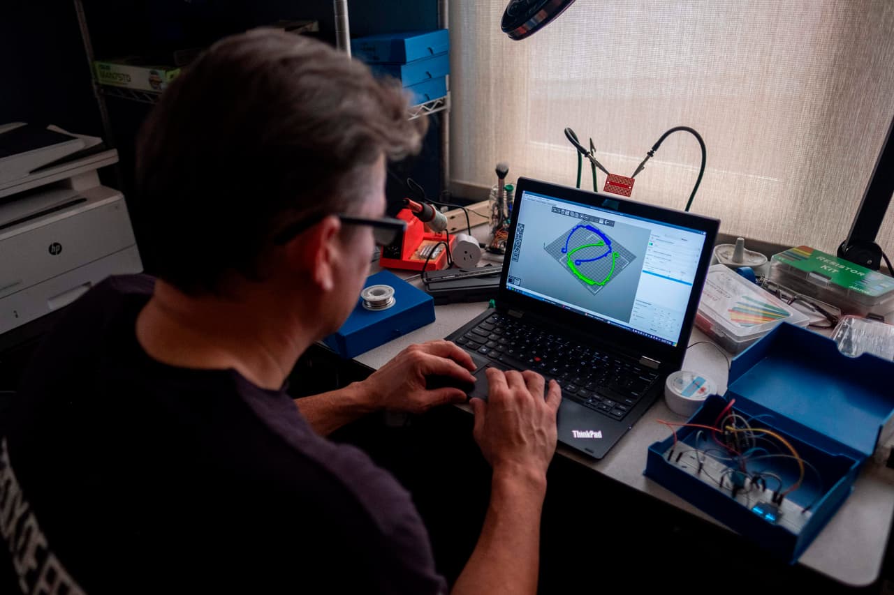 El Dr. Jonathan Alistair trabaja en un software de impresora 3D para hacer marcos para protectores faciales en San Juan.