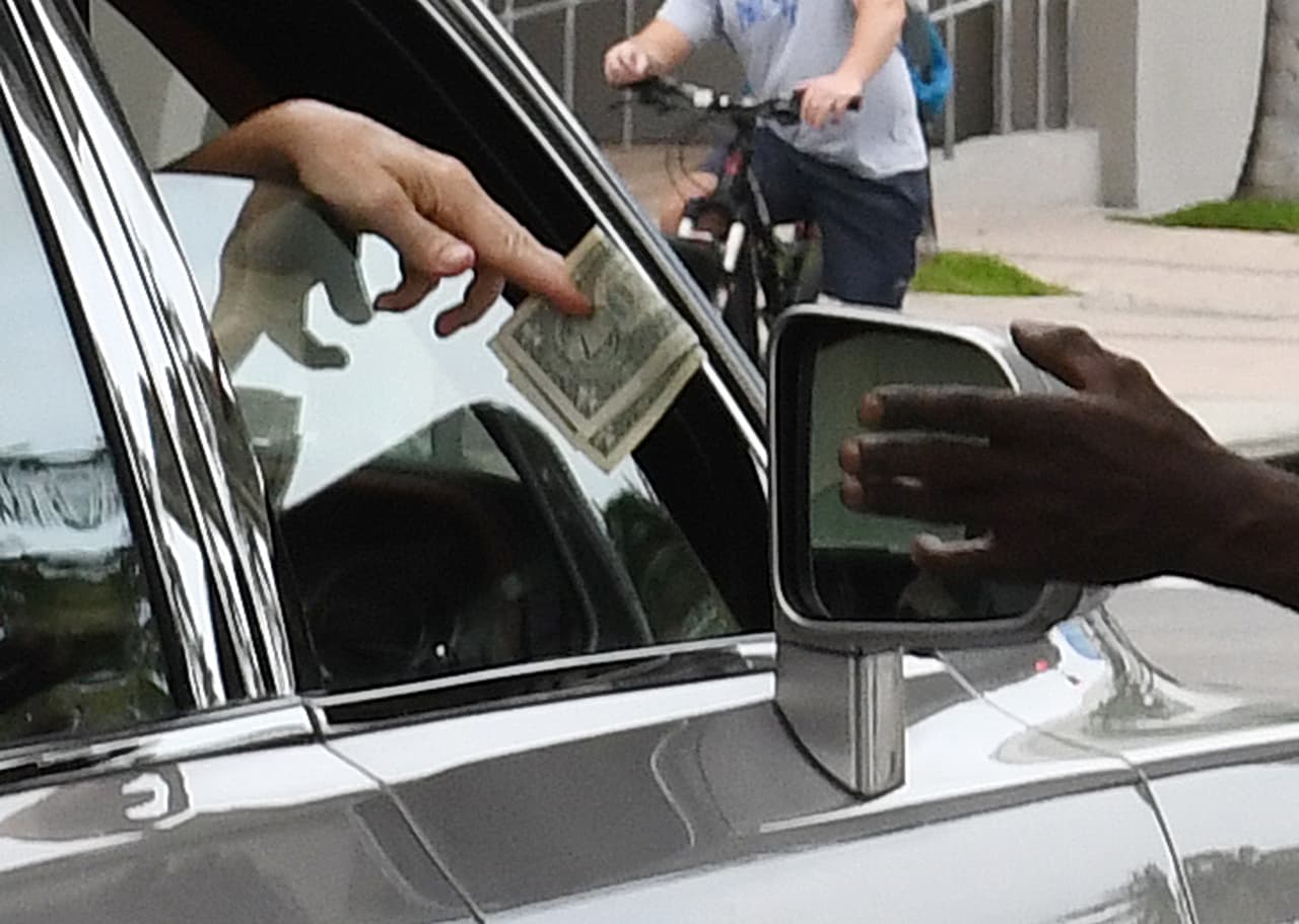 La persona que iba en el asiento delantero del pasajero, bajó la ventana y regaló con unos dólares al desamparado.