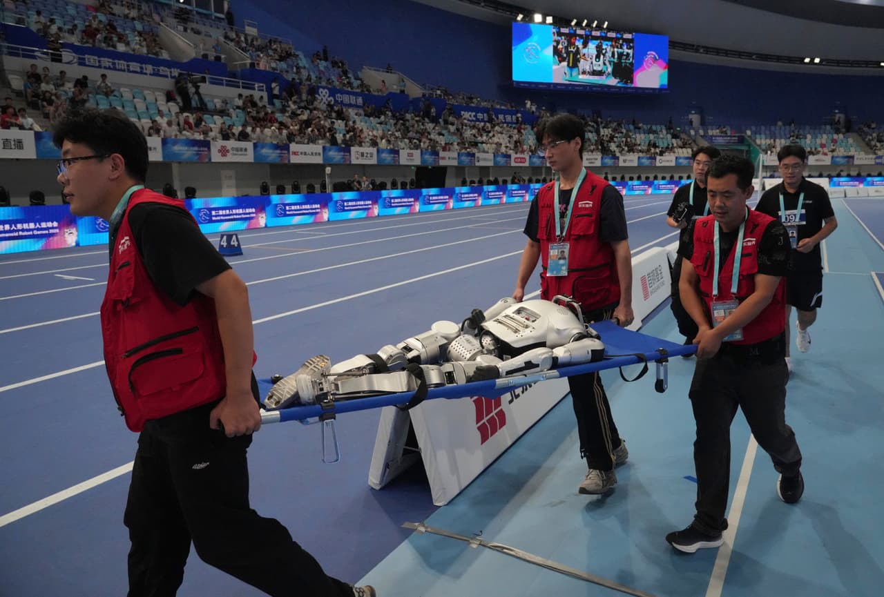 Un robot humanoide es retirado de la pista tras competir en la carrera de 1500 metros durante los Juegos Mundiales de Robots Humanoides en Pekín.