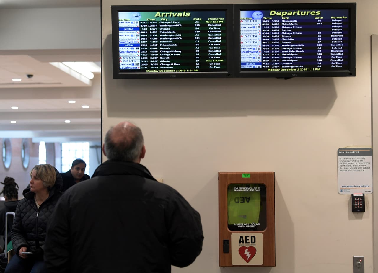 Un hombre mira el panel de estado de un vuelo cuando se reanuda el servicio después de una nevada durante la noche, en el Aeropuerto Internacional de Albany en Colonie, Nueva York, el lunes 2 de diciembre de 2019.