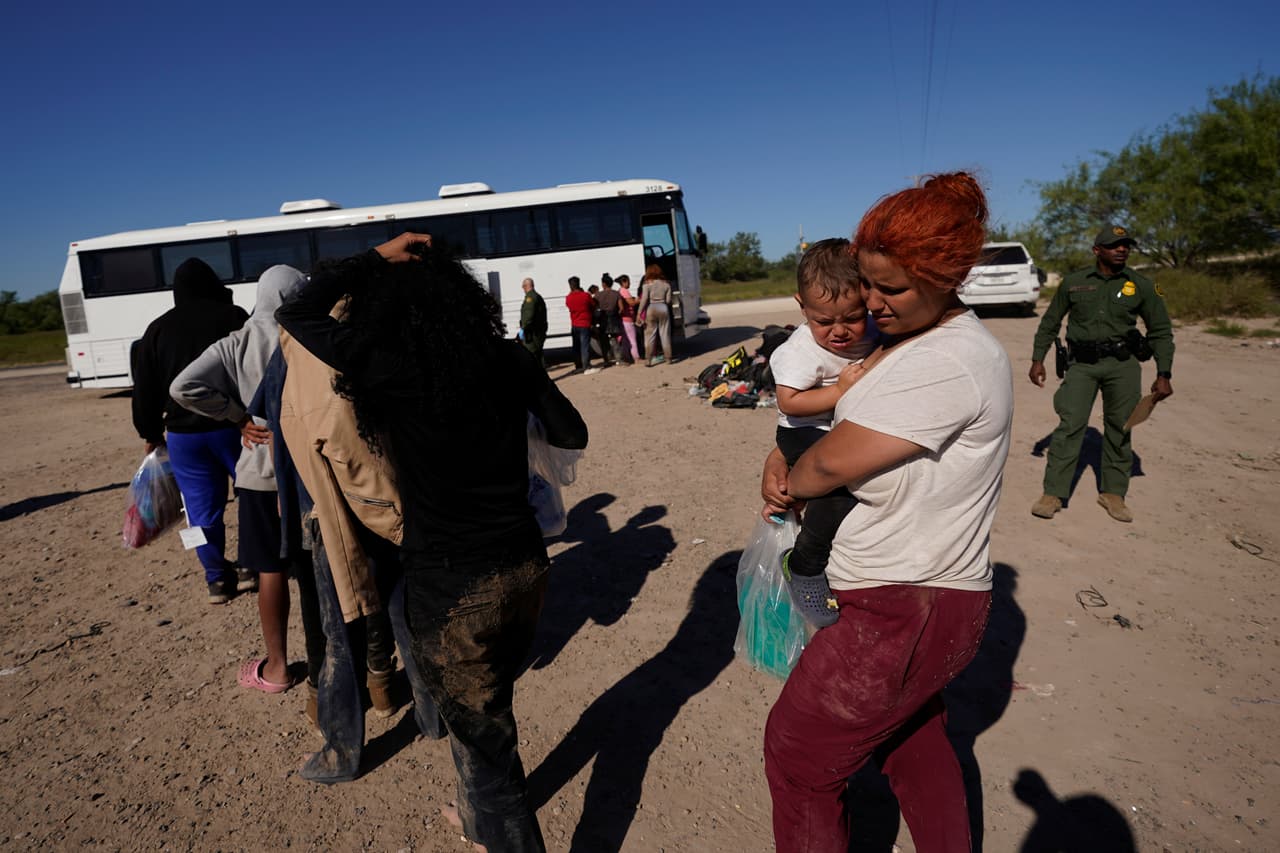 Migrantes esperan para subir a autobuses mientras son procesados por la Patrulla Fronteriza tras cruzar el río Grande y entrar en EEUU desde México.