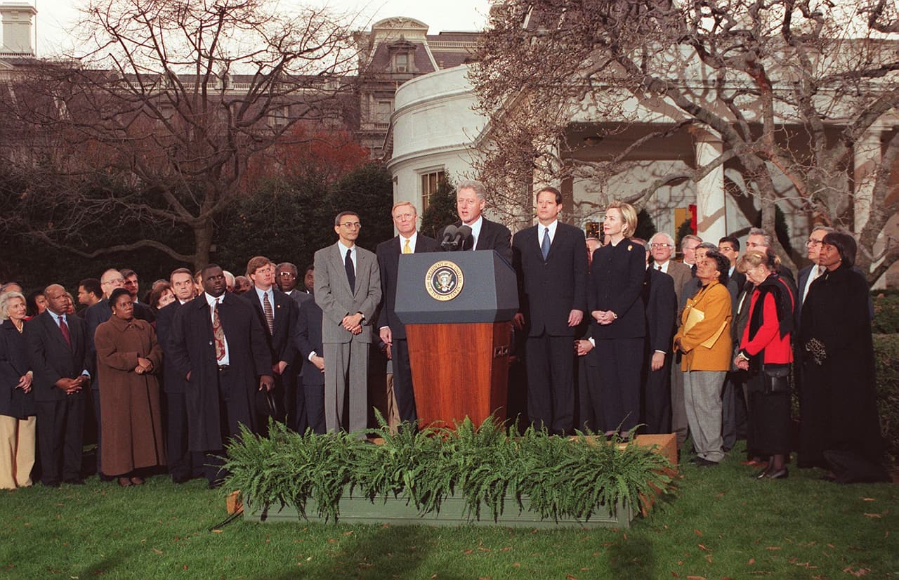 Esta foto del 19 de diciembre de 1998 muestra al presidente Bill Clinton, miembros del partido político demócrata, el vicepresidente Al Gore y la entonces primera dama Hillary Clinton frente a la Casa Blanca.