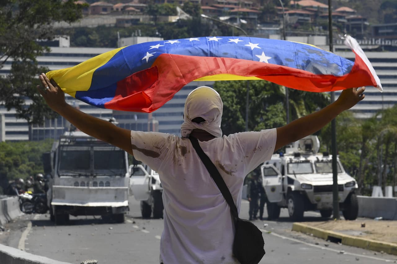 Un manifestante opuesto a Maduro enfrenta un piquete de la Guardia Nacional en Caracas.