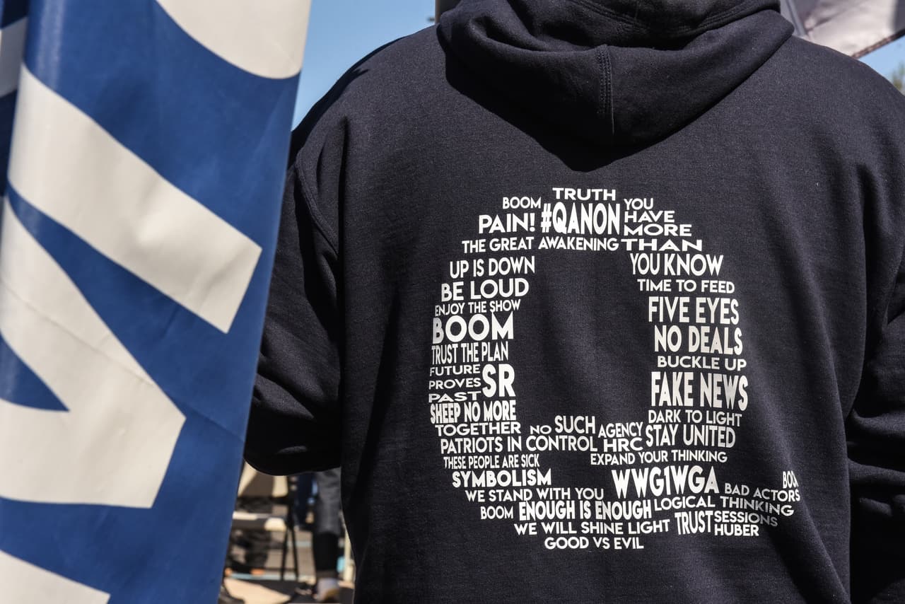 Q es uno o varios usuarios anónimos de internet. La letra es una credencial de seguridad del más alto nivel en el gobierno. 
<br>
<br>Supuestamente quien lo escribe conoce secretos de gobierno y conspiraciones nacionales e internacionales contra Trump.