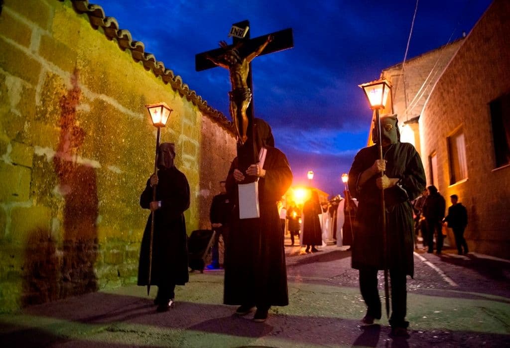 Penitentes cargan a un Cristo en la cruz denominado 'El ensogado' durante su procesión de Jueves Santo en el poblado español de Sietamo.
