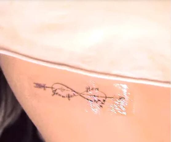 También se ve una flecha que atraviesa por en medio del símbolo. El tatuaje se encuentra en el tórax de la cantante. 
<br>