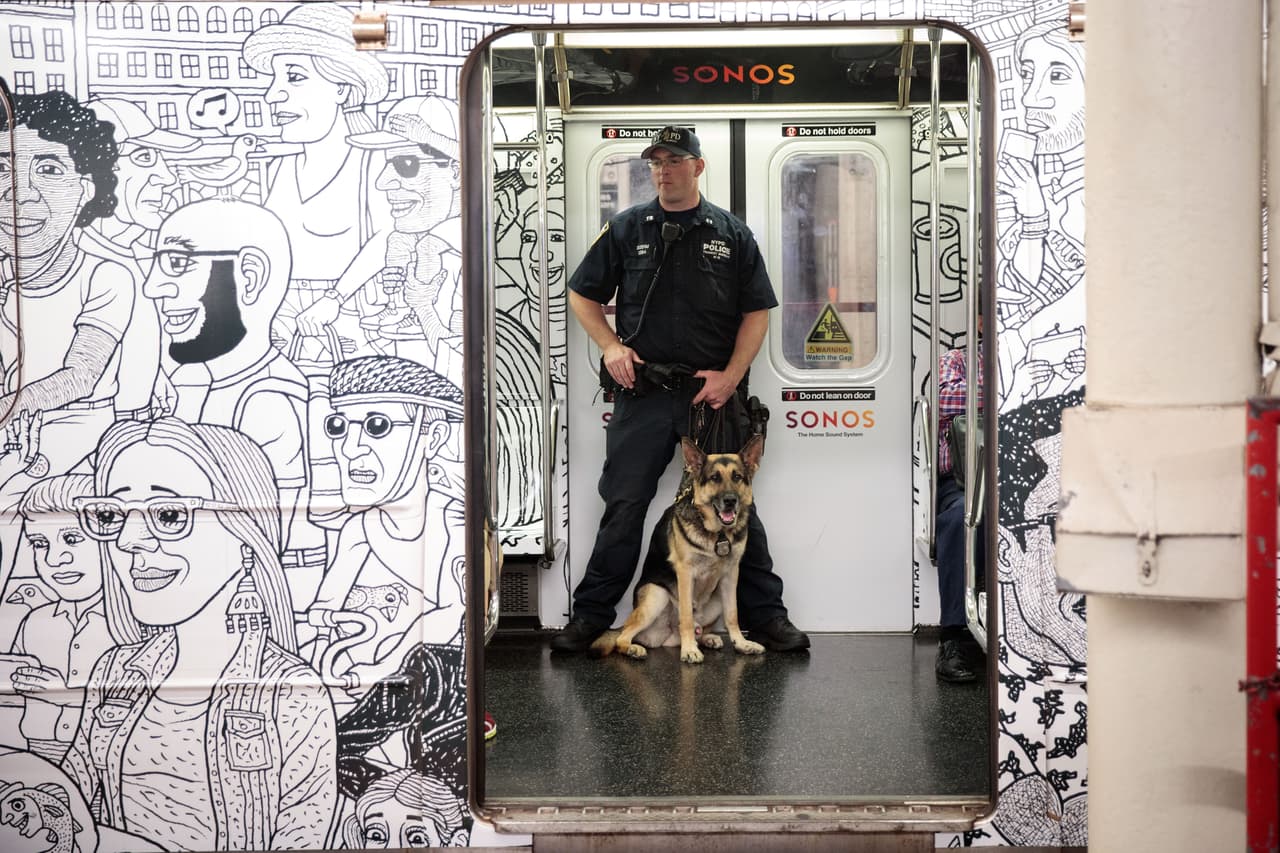 Oficiales junto a miembros de la unidad canina ofrecen vigilancia dentro de los vagones de los trenes de la ciudad de Nueva York.