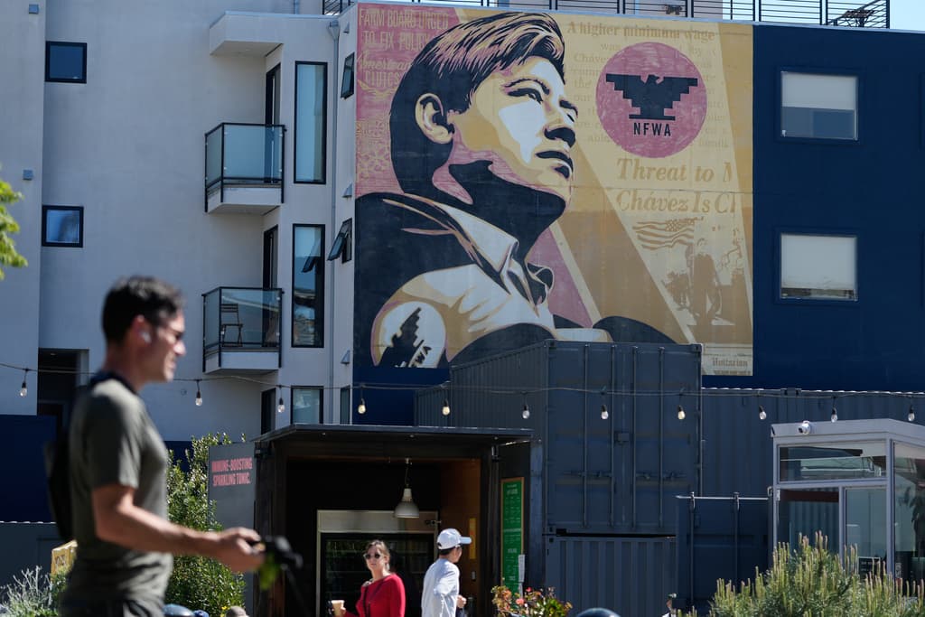 Unos peatones pasan bajo una imagen de César Chávez en un mural de San Francisco, el miércoles 18 de marzo de 2026.