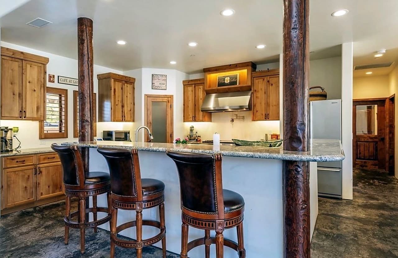 En la cocina se encuentra una isla que sirve también como desayunador para tres personas con sillas altas de madera y acolchonados en negro.