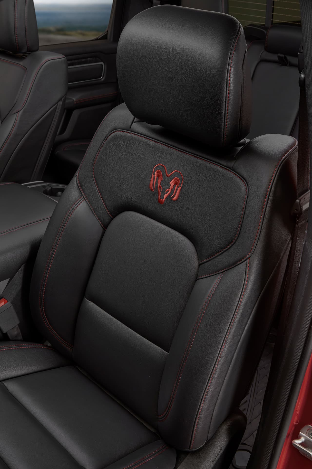 Cuenta con 
<b>asientos Premium Katzkin</b> de piel negra con la imagen del carnero de la marca RAM bordado en hilo rojo en los respaldos. Este color se repite en las costuras de asientos, paneles de puertas y consola central.