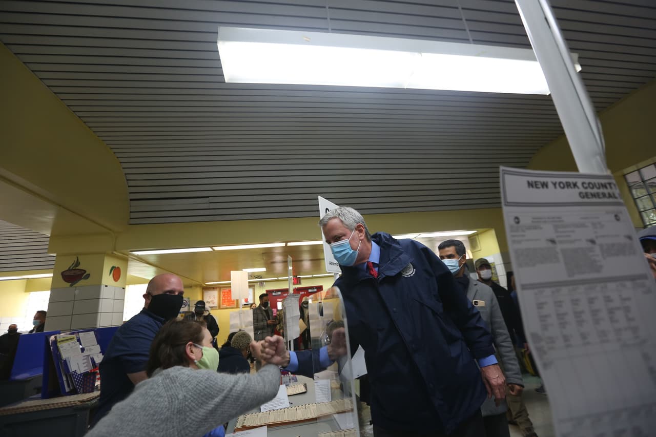 Alcalde de Nueva York Bill de Blasio saluda con su mano a la trabajadora electoral en la escuela PS 173 en Washington Height, Manhattan. Durante la pandemia el colegio electoral dicto una serie de regulaciones para evitar el contagio del coronavirus: Distanciamiento Social, usar mascarillas y lavarse las manos.