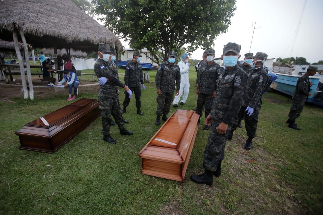 Militares permanecen junto a dos féretros con los cuerpos de dos personas que murieron en un bote que se volcó este jueves, en la Base Naval de Cataratas, en Honduras.