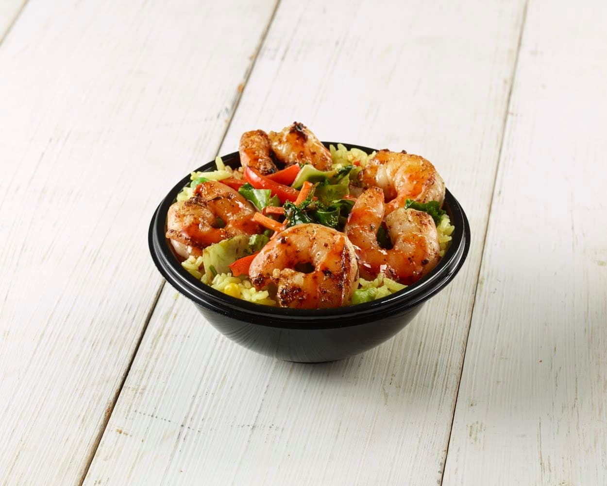 CALYPSO ISLAND SHRIMP BOWL - Repollo tropical sabroso y colorido salteado con zanahorias frescas, cebolleta, jengibre y pimientos rojos dulces, servido en un arroz tropical amarillo cubierto con camarones caribeños (marinados) a la parrilla herbáceos y un glaseado tropical dulce y picante.