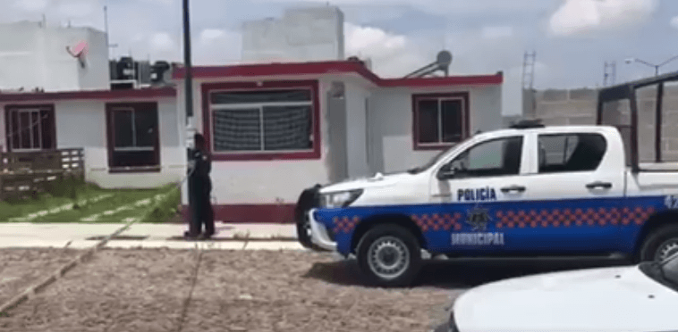 Vehículos de la Policía Municipal en la casa de San Juan del Río, Querétaro, donde fueron encontrados los cadáveres.