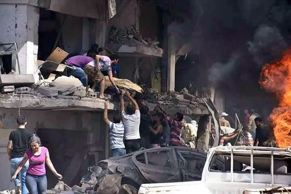 Varias personas trasladan el cuerpo de un fallecido en el atentado en la ciudad de Qamishli, en Siria.