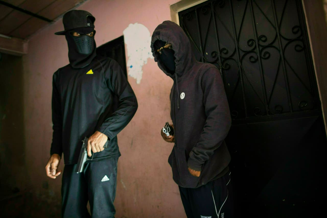 'El Negrito' (derecha) y 'Dog' (izquierda), dos miembros de la pandilla Crazy Boys, sostienen sus armas en un piso franco en Petare, en Caracas.